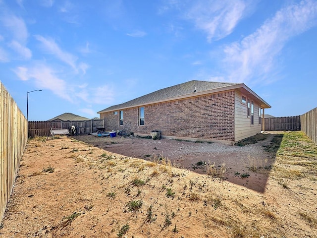 view of property exterior with a fenced backyard and brick siding