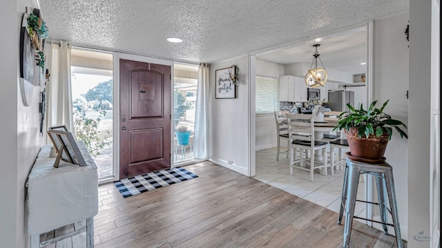 foyer entrance with a textured ceiling and light hardwood / wood-style floors