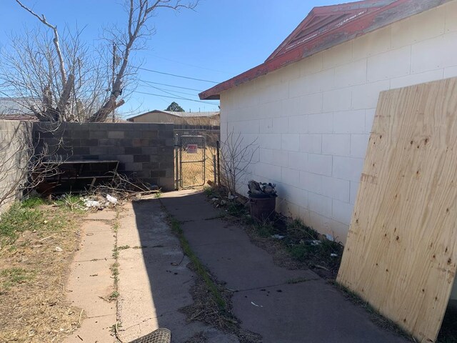 view of side of property with concrete block siding, a gate, and fence