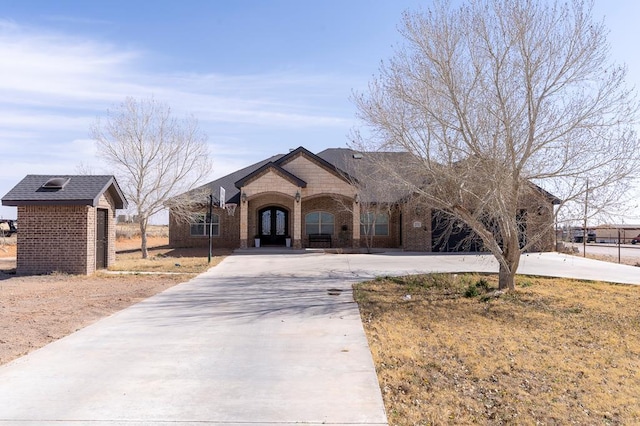 view of front of house featuring driveway, brick siding, and an outdoor structure