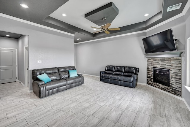 living area with a ceiling fan, a tiled fireplace, a tray ceiling, recessed lighting, and baseboards