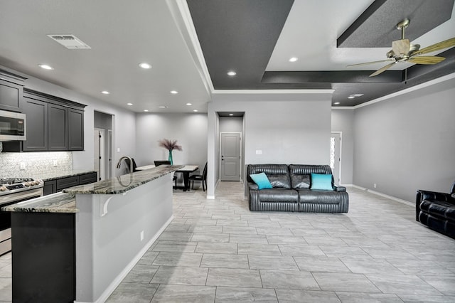 kitchen with visible vents, light stone counters, open floor plan, appliances with stainless steel finishes, and ceiling fan