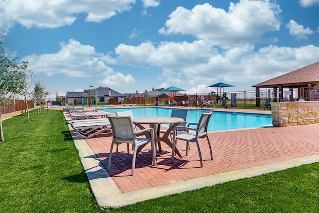 community pool featuring a patio area, a lawn, and fence