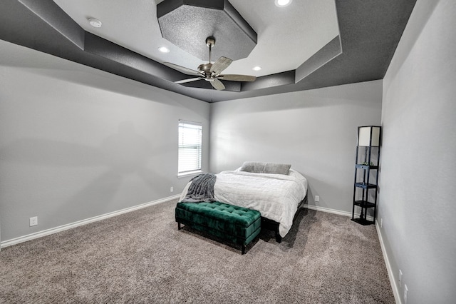 bedroom featuring recessed lighting, a tray ceiling, baseboards, and carpet floors