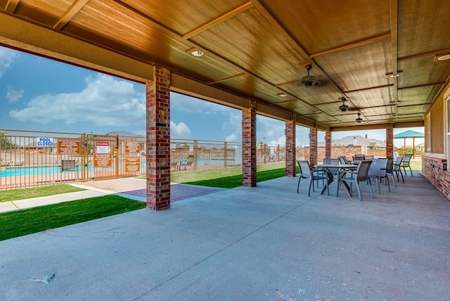 view of patio featuring outdoor dining space, a community pool, and fence