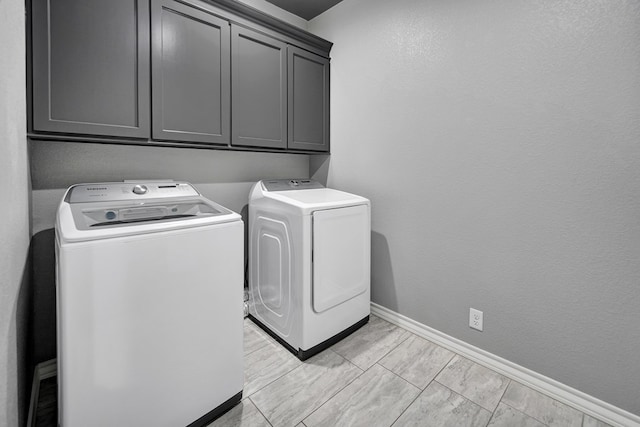 laundry area with baseboards, cabinet space, and washer and clothes dryer