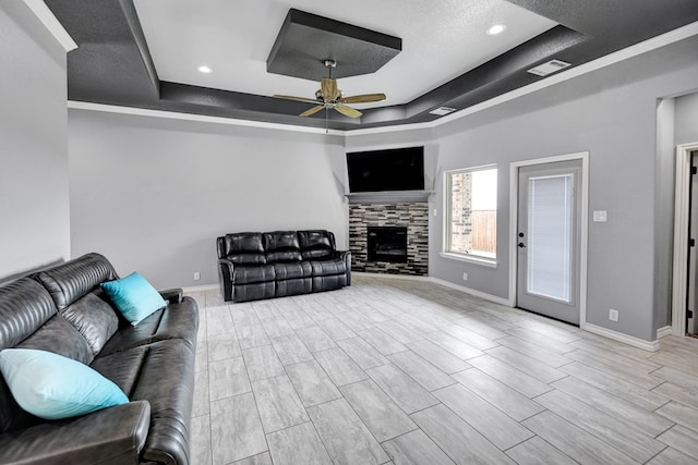 living area with visible vents, baseboards, a raised ceiling, and a ceiling fan