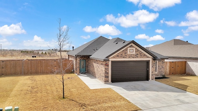 view of front facade featuring brick siding, driveway, an attached garage, and fence