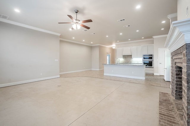 unfurnished living room featuring crown molding, a brick fireplace, sink, and ceiling fan