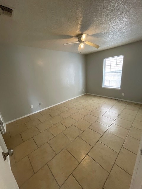 spare room with light tile patterned floors, a textured ceiling, and ceiling fan