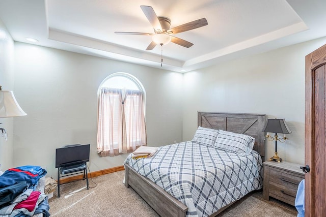 bedroom featuring carpet, a raised ceiling, and ceiling fan