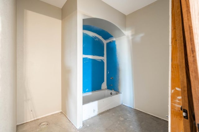 bathroom featuring a tub to relax in and concrete floors