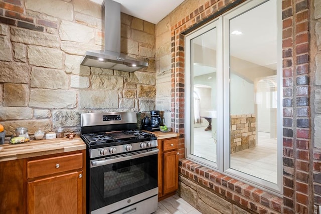 kitchen featuring stainless steel gas stove, wood counters, and exhaust hood