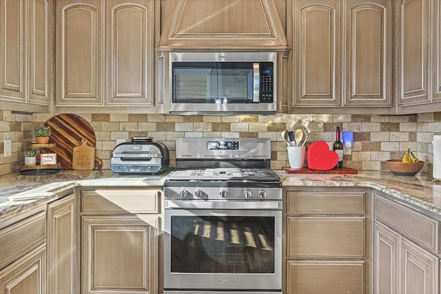 kitchen with decorative backsplash, light stone countertops, and appliances with stainless steel finishes