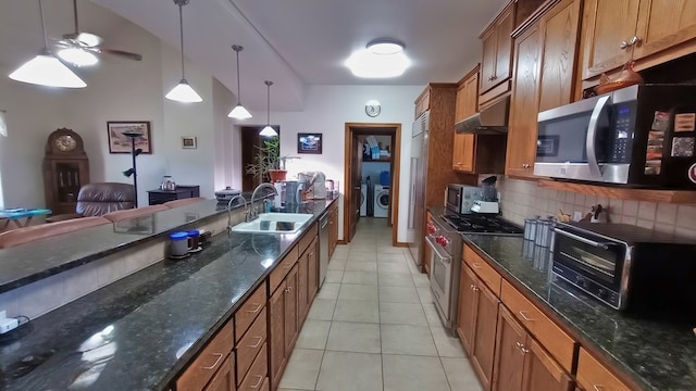 kitchen with stainless steel appliances, sink, pendant lighting, light tile patterned floors, and washer / clothes dryer