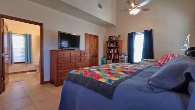 bedroom featuring a high ceiling, ensuite bathroom, light tile patterned floors, and ceiling fan