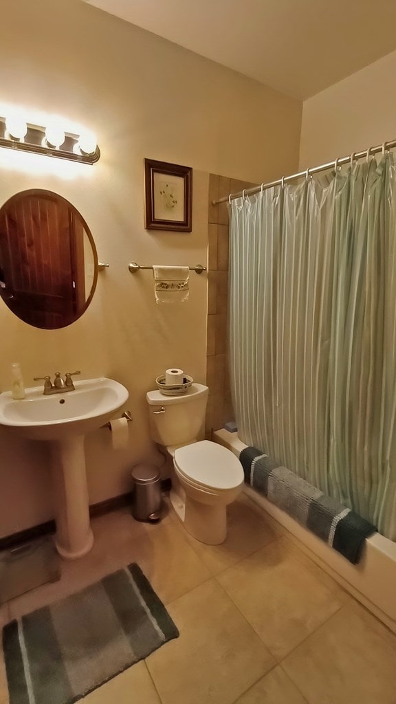 full bathroom with tile patterned floors, sink, shower / bathtub combination with curtain, and toilet