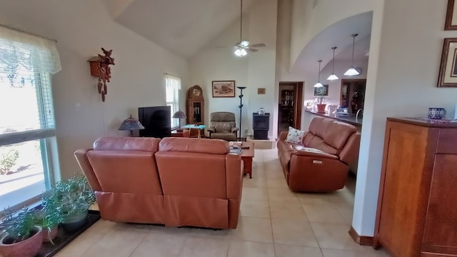 tiled living room with ceiling fan, plenty of natural light, and high vaulted ceiling