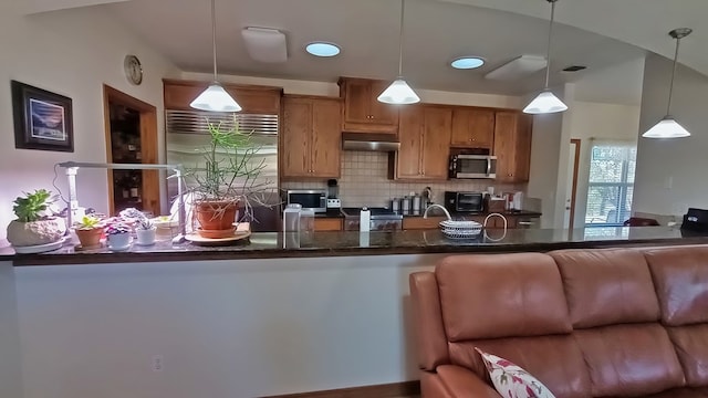 kitchen featuring appliances with stainless steel finishes, backsplash, vaulted ceiling, sink, and pendant lighting