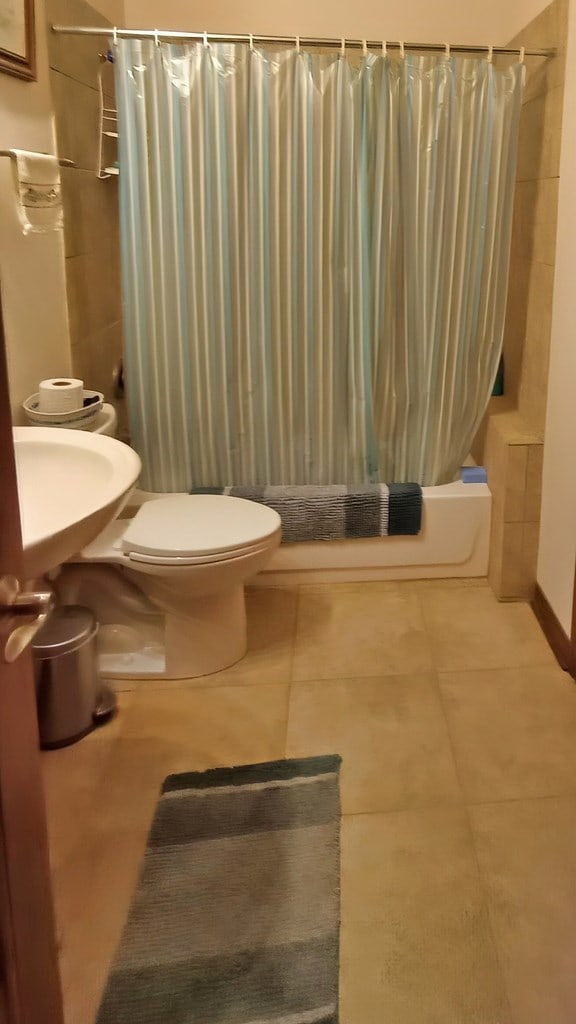 full bathroom with shower / bath combination with curtain, toilet, and sink