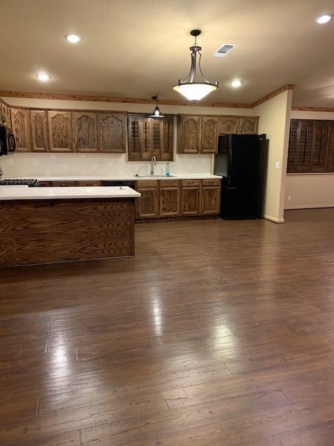 kitchen featuring pendant lighting, light countertops, visible vents, a sink, and black appliances