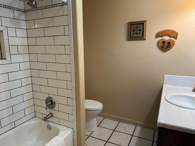 bathroom with baseboards, toilet, tile patterned flooring, tub / shower combination, and vanity