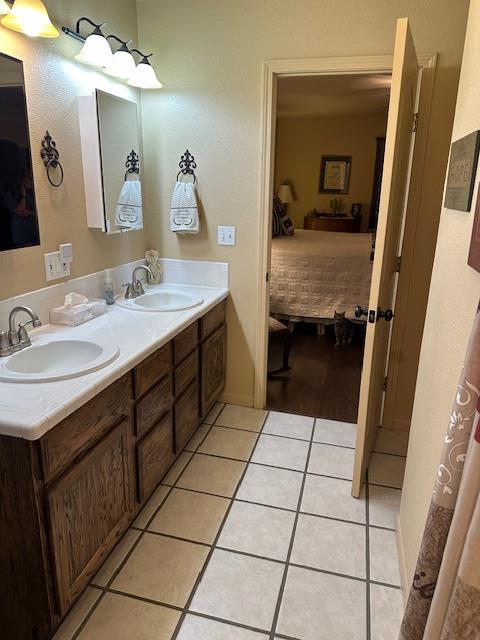 bathroom with tile patterned flooring, double vanity, a sink, and ensuite bathroom