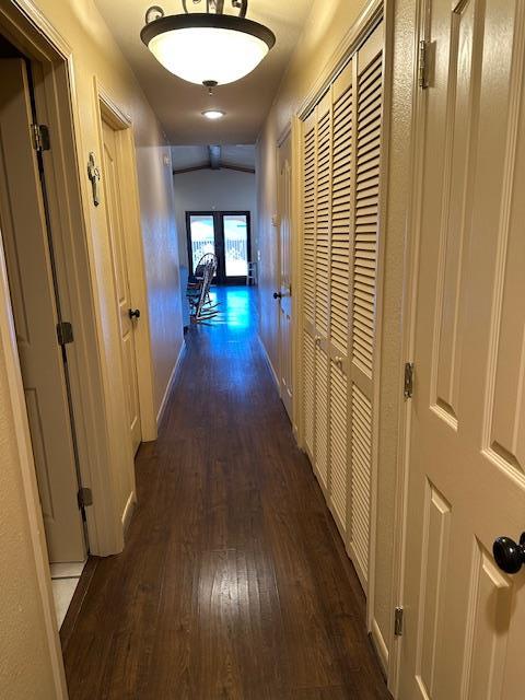 hall featuring dark wood-type flooring and baseboards