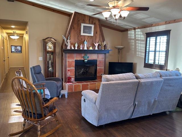 living area with lofted ceiling, dark wood-style floors, ceiling fan, and a fireplace