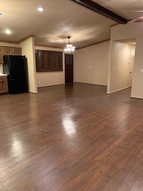 unfurnished living room with lofted ceiling with beams, baseboards, visible vents, and dark wood-type flooring