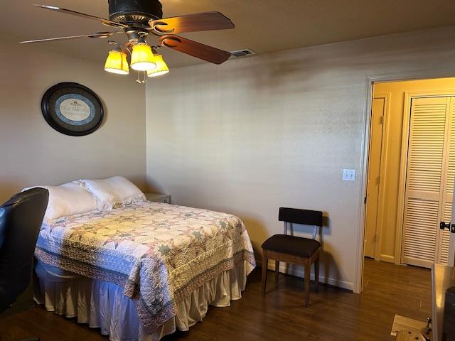 bedroom featuring dark wood-style floors, visible vents, ceiling fan, and baseboards