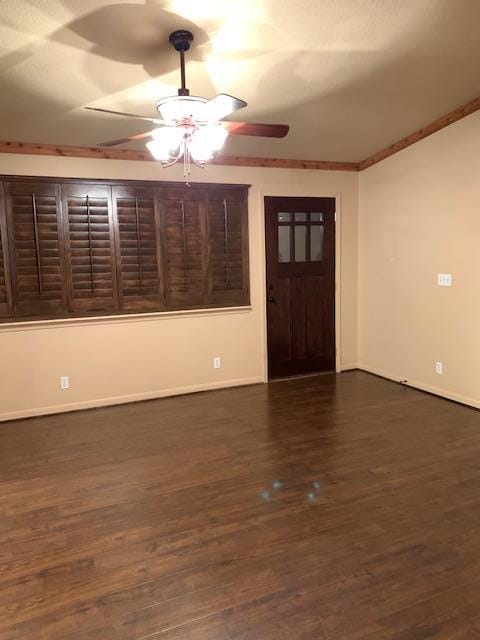 unfurnished room featuring a ceiling fan, dark wood-style flooring, and baseboards