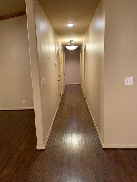 hallway with dark wood-style floors and baseboards