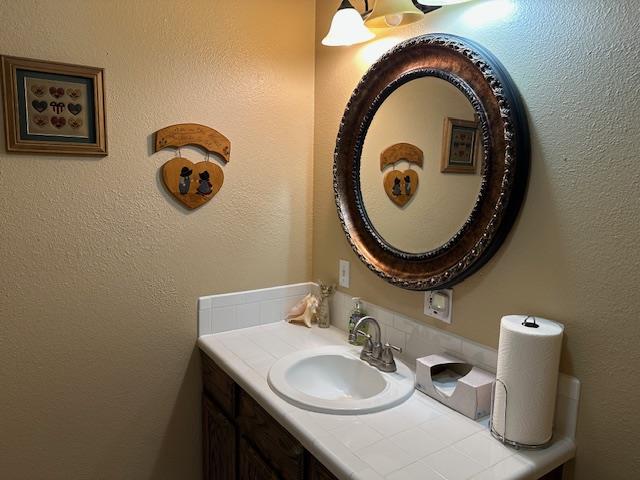 bathroom with a textured wall and vanity