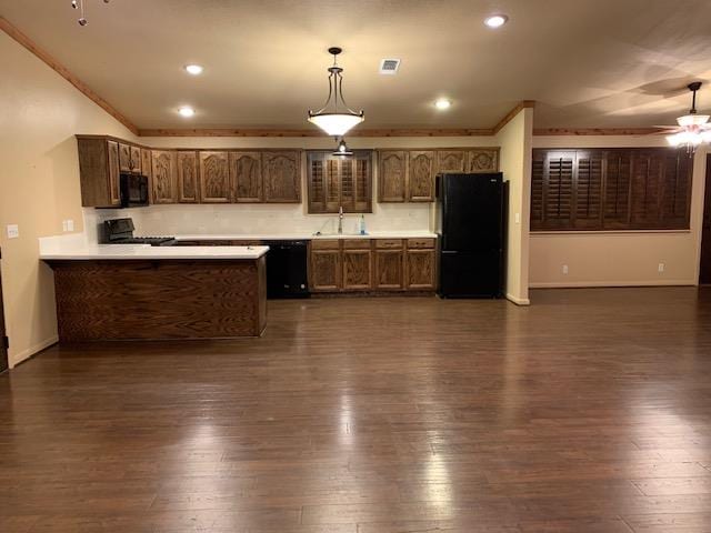 kitchen featuring decorative light fixtures, a peninsula, light countertops, black appliances, and a sink