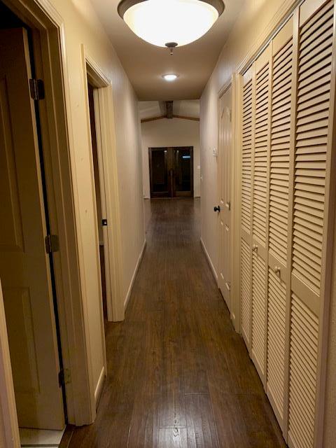 corridor featuring baseboards and dark wood-type flooring