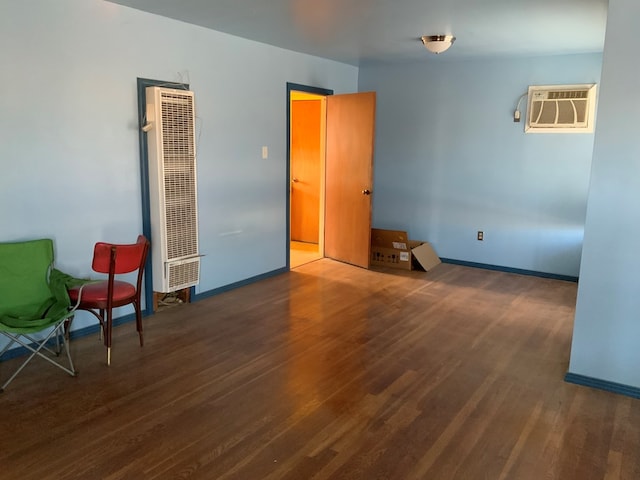 spare room with a wall unit AC and dark hardwood / wood-style flooring