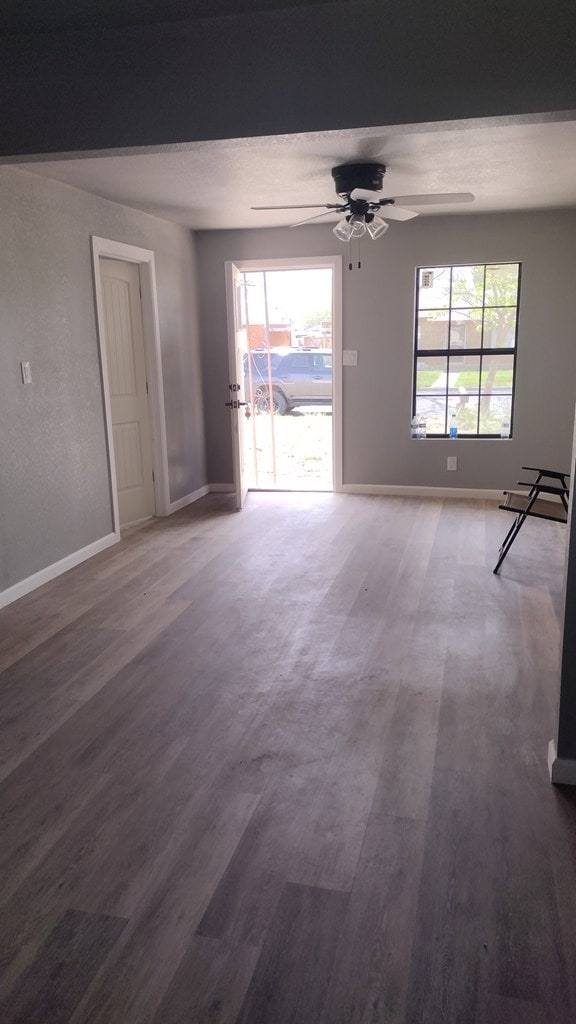 empty room featuring ceiling fan, hardwood / wood-style floors, and a healthy amount of sunlight