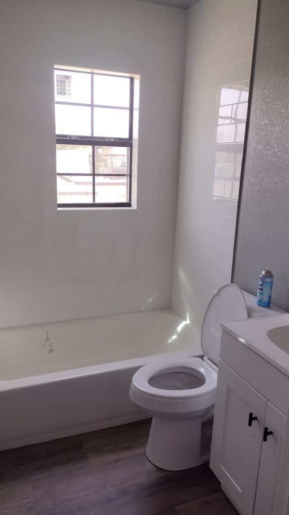 full bathroom featuring wood-type flooring, vanity, toilet, and tiled shower / bath combo