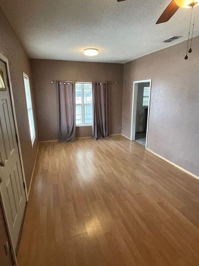 interior space featuring light hardwood / wood-style flooring, ceiling fan, and a textured ceiling