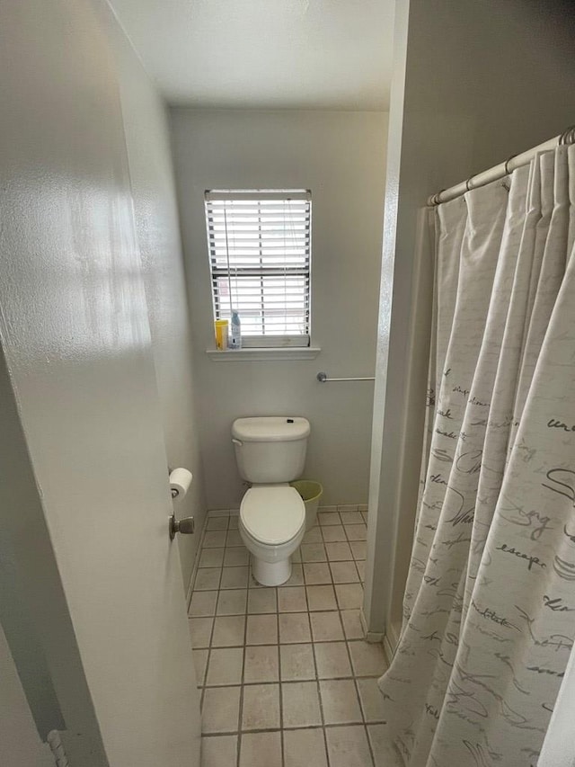 bathroom featuring a shower with shower curtain, tile patterned flooring, and toilet