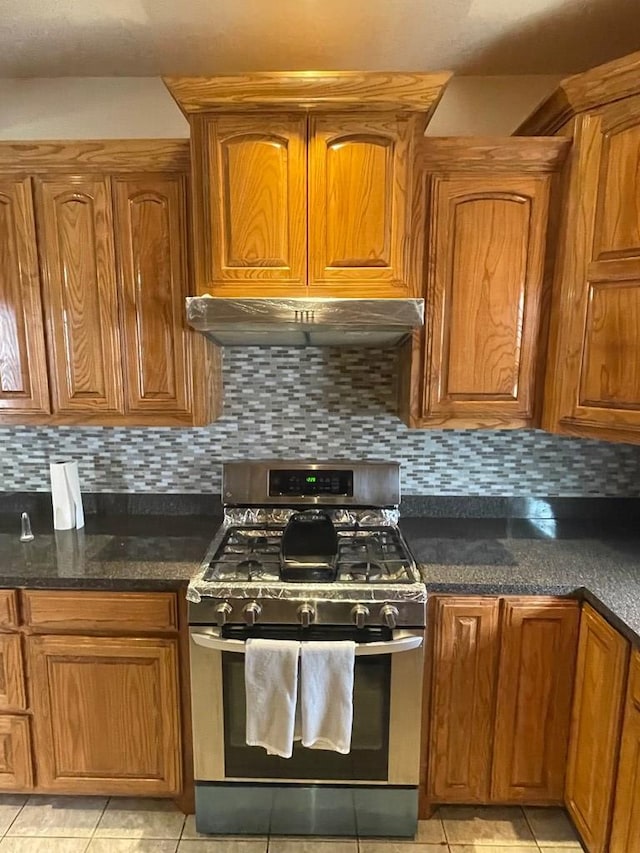 kitchen with light tile patterned flooring, backsplash, and stainless steel range with gas stovetop