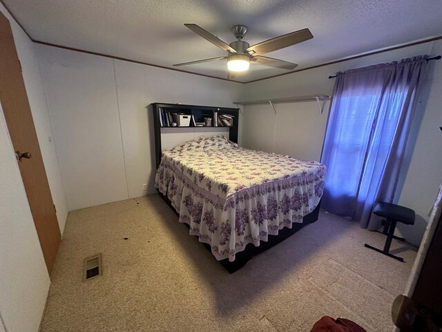 carpeted bedroom featuring ceiling fan and a textured ceiling