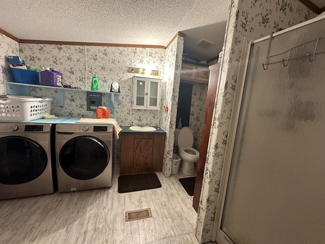 bathroom featuring a textured ceiling, crown molding, sink, separate washer and dryer, and hardwood / wood-style flooring