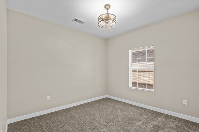 carpeted spare room with a notable chandelier