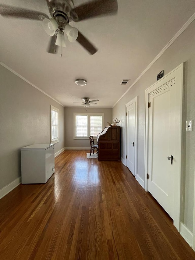 interior space with ornamental molding, ceiling fan, and dark wood-type flooring