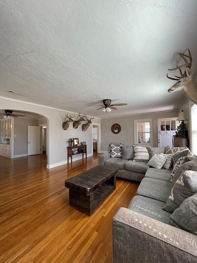 living room featuring ceiling fan, wood-type flooring, and a textured ceiling