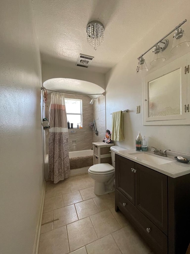 full bathroom featuring tile patterned floors, vanity, a textured ceiling, shower / bath combo with shower curtain, and toilet