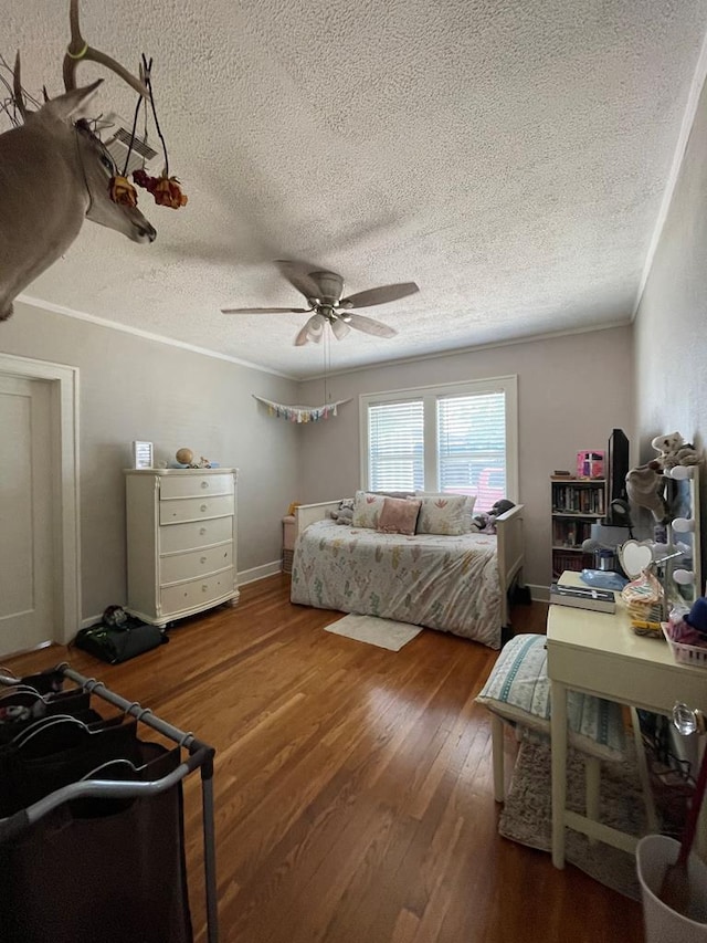 bedroom featuring hardwood / wood-style floors, ceiling fan, ornamental molding, and a textured ceiling