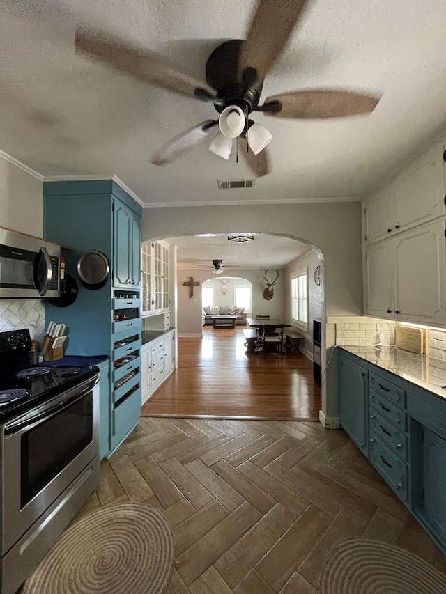 kitchen with a textured ceiling, stainless steel appliances, tasteful backsplash, and ornamental molding